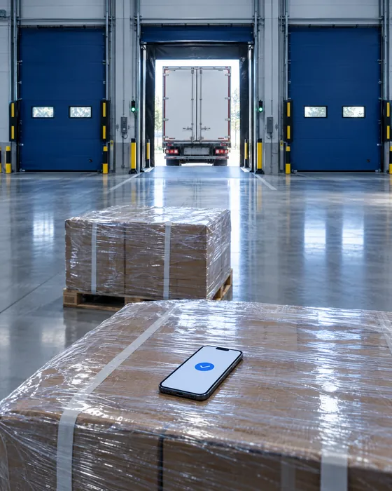 Een laaddok met blauwe dokdeuren; op de pallet ligt een telefoon met de bevestigde levering